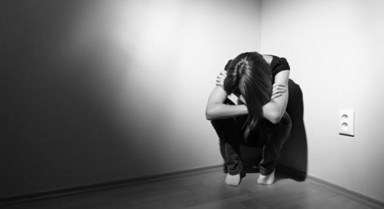 Imagem em preto e branco de pessoa encolhida em um canto, representando um paciente com sofrimento mental