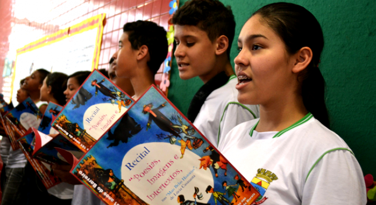 Cerca de seis alunos da Rede Municipal de Ensino Fazem recital com livro na mão.