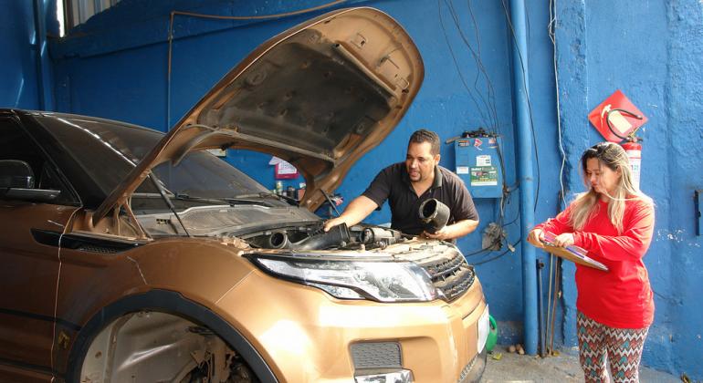 BH em Pauta: Parceria leva conhecimento para empreendedores Mecânico mexe no carro, que está com o capô levantado, e mulher está do lado, com prancheta na mão