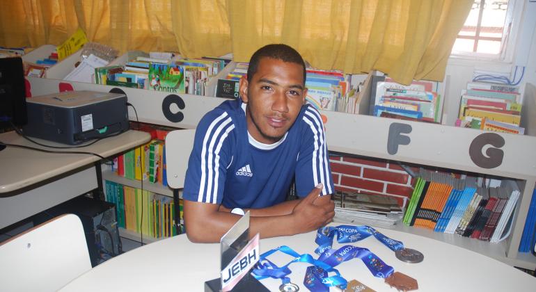 BH em Pauta: Esporte é ferramenta no processo educacional Técnico Daniel em biblioteca da E.M. Governardor Ozanan Coelho com várias medalhas