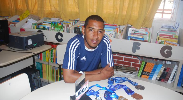 Técnico Daniel em biblioteca da E.M. Governardor Ozanan Coelho com várias medalhas