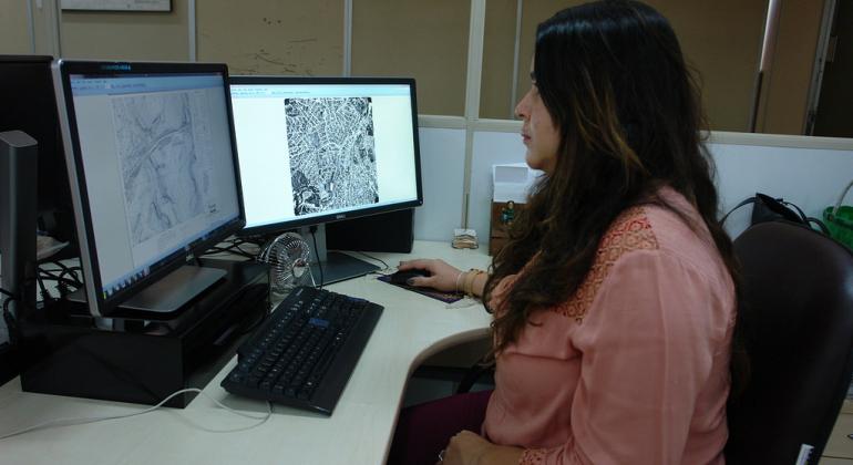 A servidora Thaísa Santos Faria está usando computador, com dois monitores. Nos dois, mapas estão abertos.