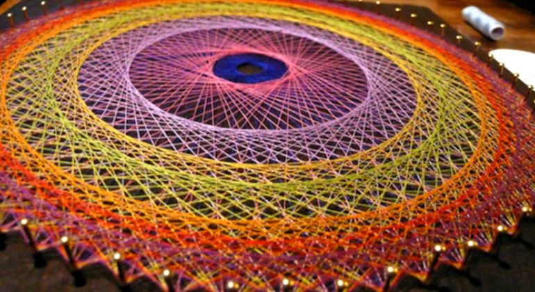 Prefeitura oferece curso gratuito de String Art nesta sexta-feira, dia 1º de setembro, no Centro de Educação Ambiental da Pampulha. Foto: Divulgação Trabalho circular com barbantes nas cores vermelhoa, amarela, laranja, rosa e rosa fluorescente, em forma de mandala.