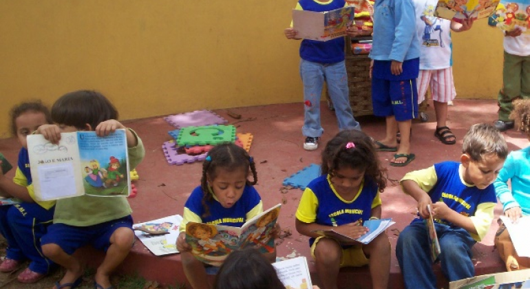 Além da visita, estudantes terão a chance de escolher livros nos estandes e participar de projetos para incentivo à leitura na escola. Foto: Viviane Maia Dez crianças de idade entre 4 e 5 anos lendo livros infantis.