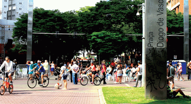 Mais de dez pessoas andam de bicicleta em rua interditada na Savassi durante o dia. 