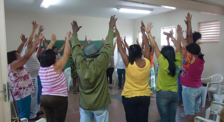 Idosos com as mãos para cima fazendo exercício