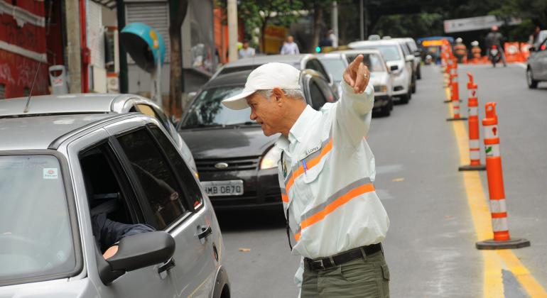 Agente de trânsito da BHTrans dá orientações a motoristas em rua com sinalização. 