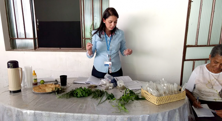 Oficineira apresentando plantas medicinais para alunas.
