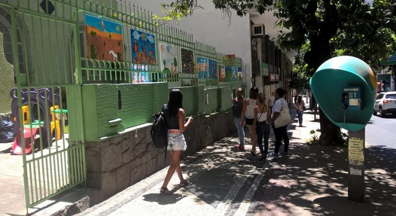 Foto: Divulgação PBH Dez telas pintadas por alunos em frente a E. M. Delfim Moreira; cerca de cinco passantes caminham pela calçada.