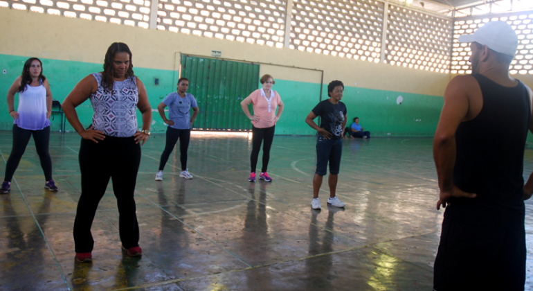 Cerca de cinco alunos praticam aulas gratuitas de dança em quadra escolar.