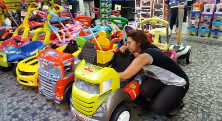 Consumidores devem ficar atentos às condições de segurança dos brinquedos. Consumidora verifica condições de segurança de um brinquedo.