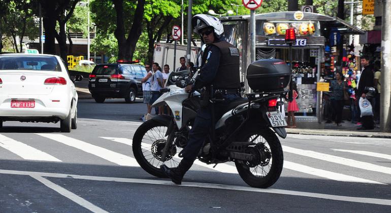 Guarda Municipal em moto no meio do trafego da cidade realizando o ser trabalho.