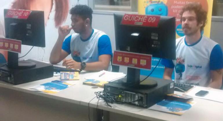 O cadastro é voltado a pessoas beneficiárias de programas sociais. Foto: Divulgação/PBH Dois atendentes no BH Resolve, em frente aos seus respectivos computadores, preparados para cadastrar as pessoas que têm direito ao kit gratuito.
