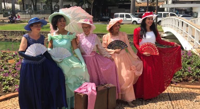 Cinco idosas usando roupas de época em um parque municipal da cidade