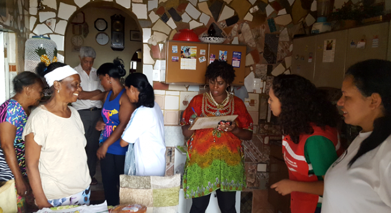 Sete mulheres e um homem em visita à casa de mosaicos de Maria Aparecida, moradora do Morro das Pedras. 