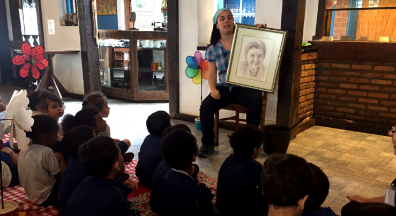 Mais de 500 crianças da Educação Infantil Municipal tiveram a oportunidade de conhecer diferentes bares e restaurantes da cidade. Foto: Divulgação Abrasel Crianças observam mulher sentada com desenho de outra mulher na mão