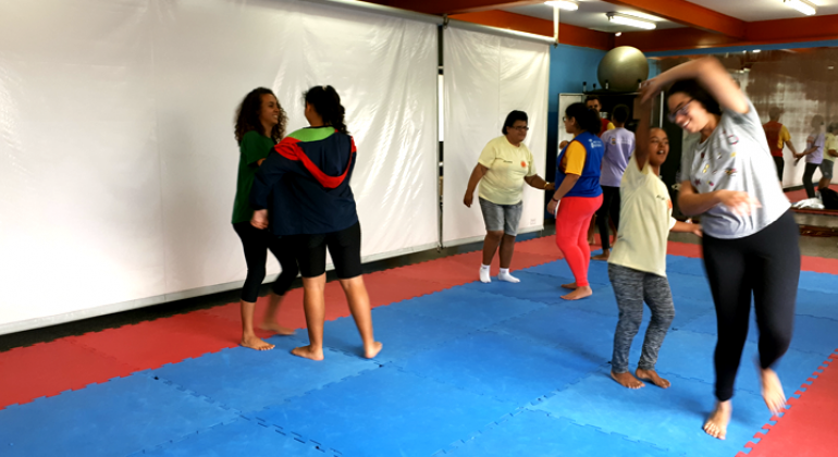 Seis jovens fazem aula de dança, reunidos dois a dois. 