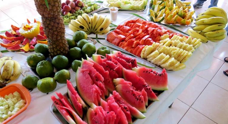 Melancia, abacaxi e frutas diversas picadas em travessas sobre a mesa