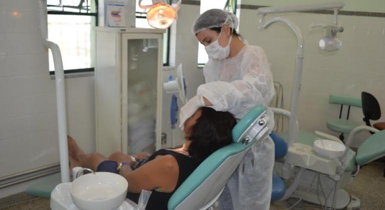 Dentista atendendo paciente em consultório. 