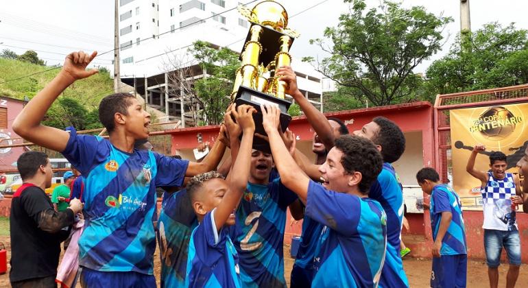 Cerca de seis jogadores mirins, dentre eles alunos do programa Esporte Esperança, seguram taça da categoria infantil da Copa Centenário.