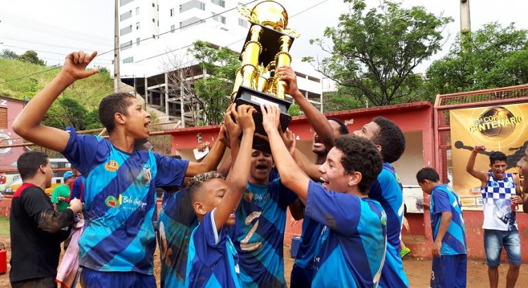 Alunos do programa Esporte Esperança integram a equipe vencedora da categoria infantil da Copa Centenário. Foto: Vilma Tomaz/PBH Cerca de seis jogadores mirins, dentre eles alunos do programa Esporte Esperança, seguram taça da categoria infantil da Copa Centenário.