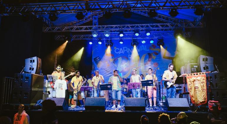 Grupo musical com sete integrantes se apresenta em um dos palcos do Carnaval de Belo Horizonte. 