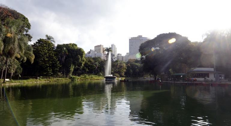Fonte de água e lago no Parque Municipal Américo Renneé Giannetti. Ao fundo, árvores do parque e prédios de Belo Horizonte.