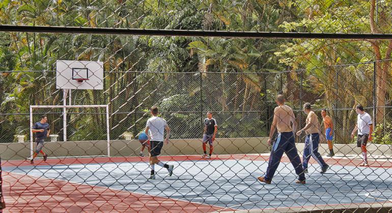 Sete homens jogam basquete em quadra no Parque