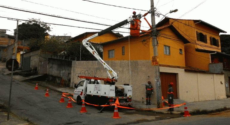 Substituição de lâmpadas convencionais por iluminação de LED começa por Venda Nova e traz tranqüilidade para moradores e comerciantes. Foto:Divulgação/PBH Homem em grua troca de lâmpadas comuns por LED nos postes do bairro Céu Azul.