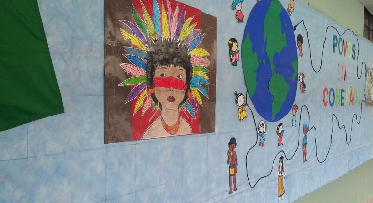 Painel da Feira de Cultura Povos em Conexão, com representação de índio e mundo.