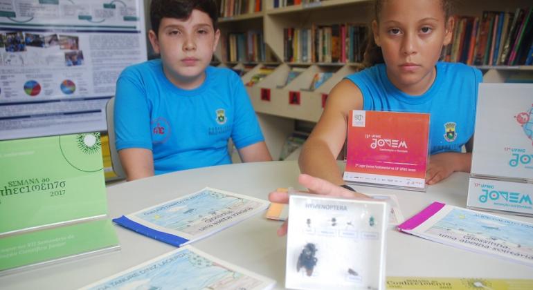 Dois alunos mostram inseto integrante de projeto de extensão “O Jardim Botânico vai à Escola”, do Museu de História Natural e Jardim Botânico da UFMG.