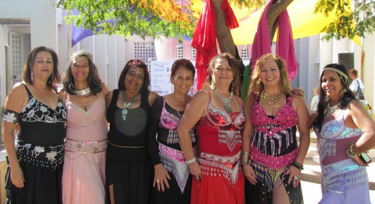 Sete mulheres vestidas de odaliscas, alunas da oficina de Dança do Ventre, posam para foto. 