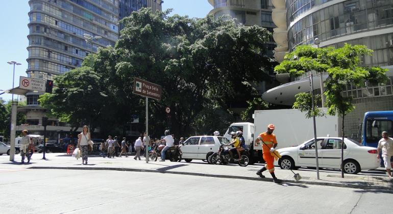 Foto: Divulgação PBH Gari limpa Praça Sete, ao fundo, carros e prédios.