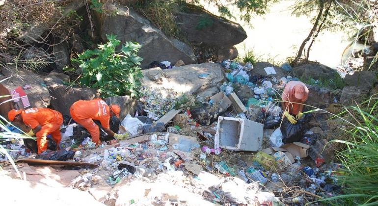 Prefeitura intensifica ações de limpeza e conta com a conscientização da população para garantir a manutenção das áreas. Foto: Mara Damasceno Três agentes da SLU limpam entulho às margens do Córrego do Onça.