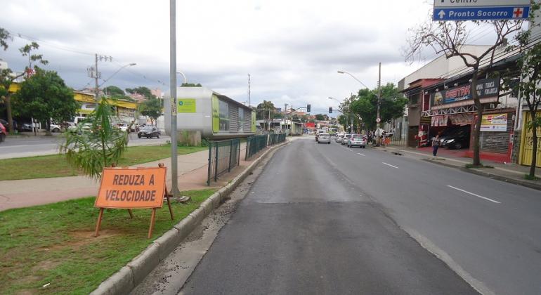 Rua com trecho recapeado e a placa com os dizeres: "Reduza a velocidade" à esquerda.