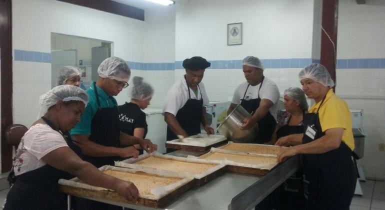 Começa, nesta semana, a produção do bolo dos 120 anos de Belo Horizonte a cargo de Renato Lobato, chef de cozinha e professor de Gastronomia. Foto: Divulgação PBH Sete pessoas arrumam quatro formas retangulares de bolo.