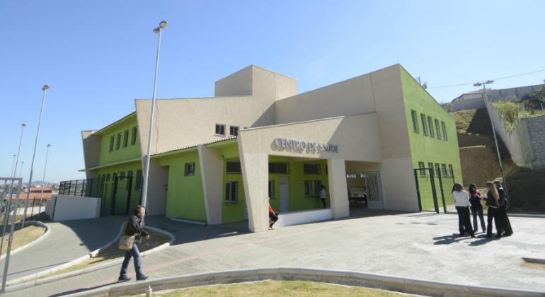 Fachada de centro de saúde com seis pessoas ao redor. Foto ilustrativa.