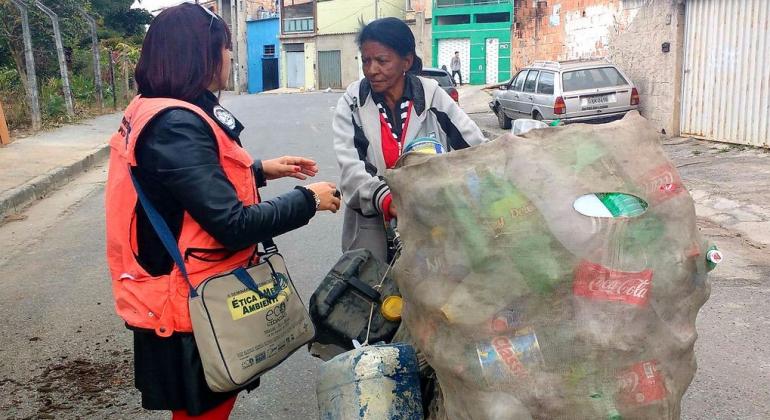 Técnica da SLU aborda catadora de lixo reciclável na rua. 