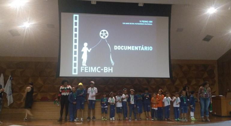 Foto: Magi Mappa/PBH Cerca de 15 alunos de escolas municipais embaixo de terão que exibe minicurtas.