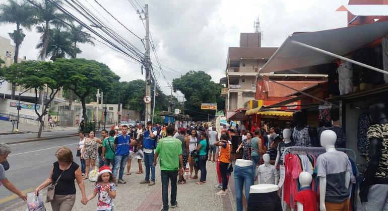 Mais de trinta pessoas fazendo compras em rua de Venda Nova, durante o dia.