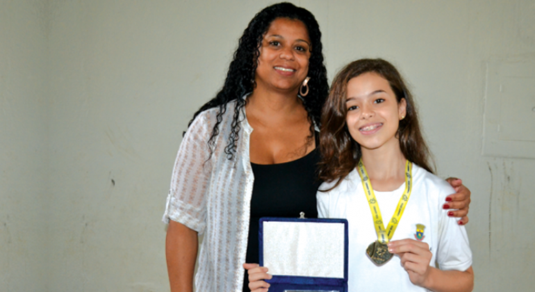 Estudantes mostram medalhas e certificado. 