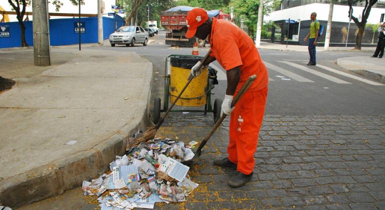 Gari recolhe lixo e panfletos na rua. 