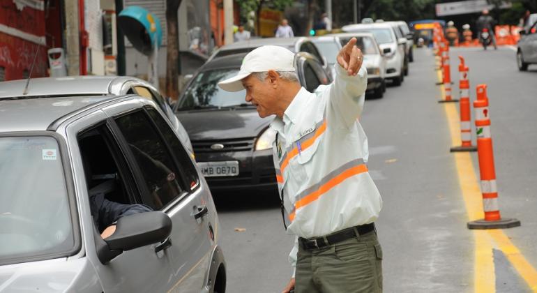 Agente de trânsito orienta carro na rua. 
