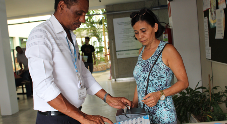 Uma das mudanças foi a emissão de senhas, para organizar e monitorar fluxo de atendimento. foto: Aline Pereira/PBH Servidor auxilia cidadã na emissão de senha para atendimento.