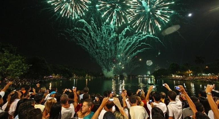 Mais trinta pessoas, na orla da Lagoa da Pampulha, brindam e vêem os fogos de Reveillon.