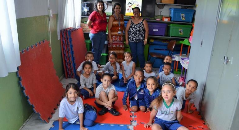 Ação das áreas de Saúde e Educação promove palestras de conscientização de estudantes sobre o combate ao mosquito transmissor da dengue. Foto: Lilian Lopes Mais de doze crianças sentadas, ao fundo, três mulheres.