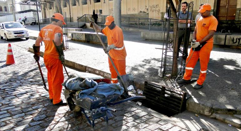 Das 60 mil bocas de lobo espalhadas pela cidade, são retiradas de 10 a 20 toneladas diárias de resíduos pela PBH via SLU. Foto: Pedro Antônio de Oliveira/PBH Três garis tiram grande volume de resíduos de boca-de-lobo.