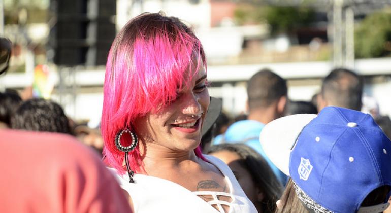 Mulher trans de cabelos cor-de-rosa sorrindo.