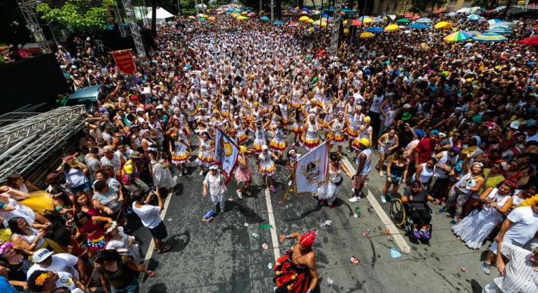 Bloco de rua desfila em via pública com grande número de espectadores