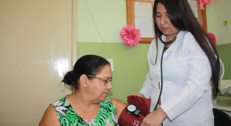 Enfermeira tira a pressão de paciente em centro de saúde